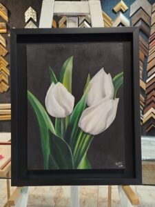 Pintura realista de tulipanes blancos con fondo oscuro, enmarcada con moldura negra moderna por Sol y Sombra SRL.