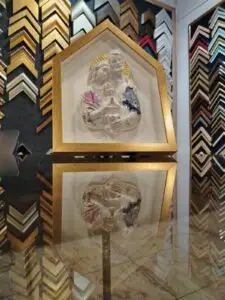 Relieve de la Sagrada Familia decorado con flores, enmarcado en moldura dorada tipo casita por Sol y Sombra SRL.