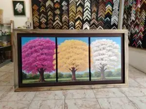 Tríptico de árboles en tonos rosado, amarillo y blanco, enmarcado con moldura de madera rústica por Sol y Sombra SRL.