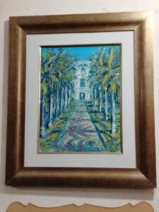 Paisaje urbano pintado con palmeras y edificio al fondo, enmarcado con moldura marrón dorada por Sol y Sombra SRL.