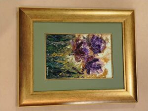 Pintura floral con tonos morados y verdes, enmarcada con moldura dorada y passepartout verde por Sol y Sombra SRL.